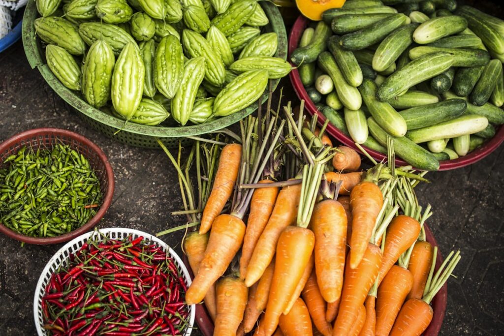 Baskets of bitter gourd, cucumber, chillies and carrots at a market